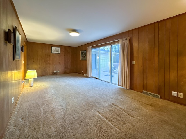 carpeted empty room featuring wooden walls