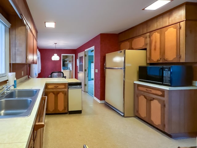 kitchen with sink, refrigerator, a notable chandelier, decorative light fixtures, and kitchen peninsula