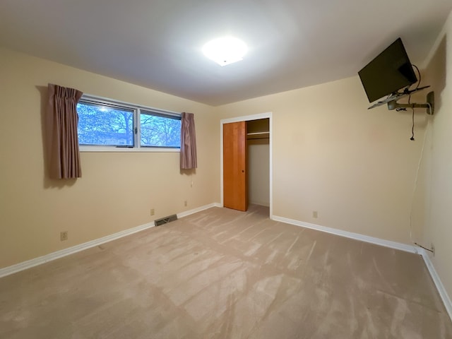 unfurnished bedroom with light carpet and a closet