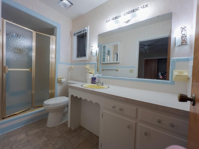 bathroom featuring vanity, toilet, a shower with door, and tile walls