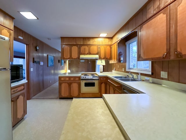 kitchen featuring white range with electric cooktop, wood walls, sink, fridge, and kitchen peninsula