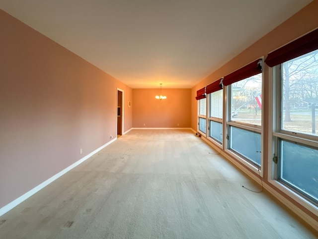 empty room with light colored carpet and a chandelier