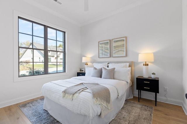 bedroom with hardwood / wood-style flooring, ceiling fan, and crown molding