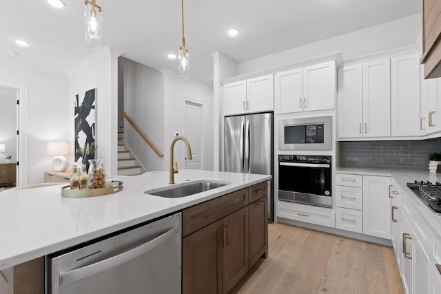 kitchen with white cabinetry, sink, pendant lighting, decorative backsplash, and appliances with stainless steel finishes