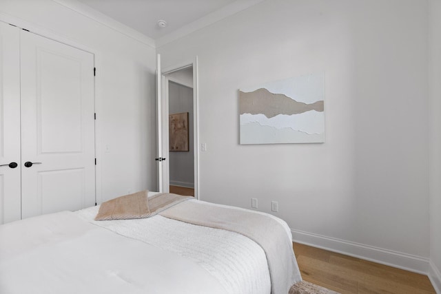 bedroom featuring hardwood / wood-style flooring, crown molding, and a closet