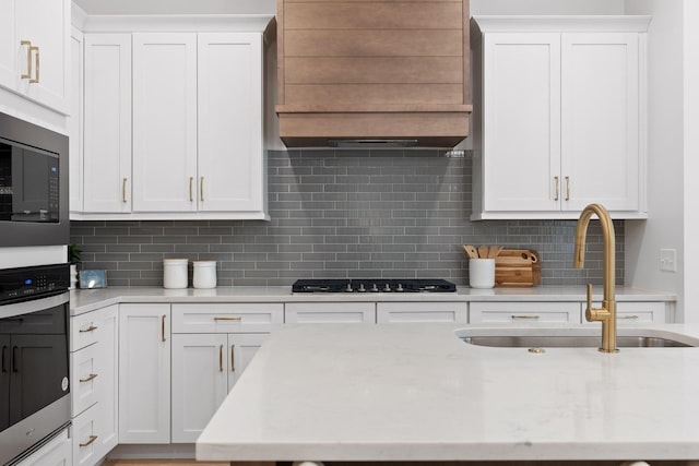 kitchen with white cabinets, decorative backsplash, sink, and oven