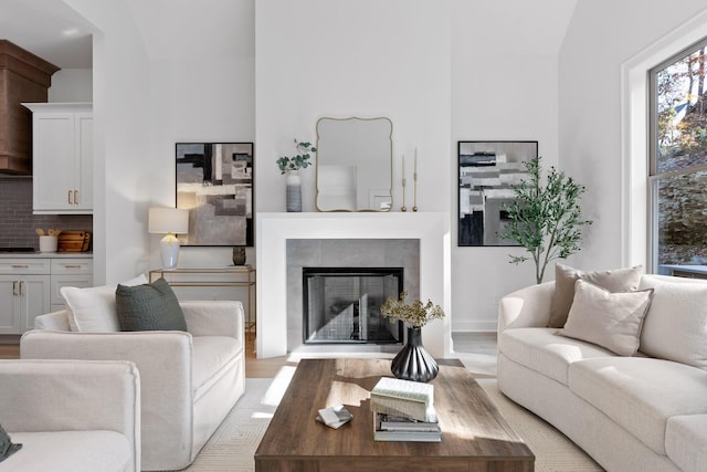 living room with a tiled fireplace, light hardwood / wood-style flooring, and lofted ceiling