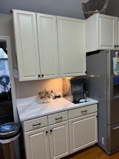 kitchen with stainless steel fridge, white cabinetry, and dark hardwood / wood-style flooring