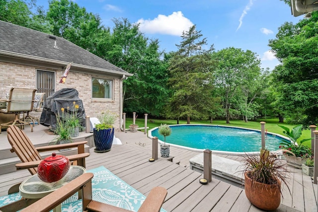 view of swimming pool with grilling area and a wooden deck