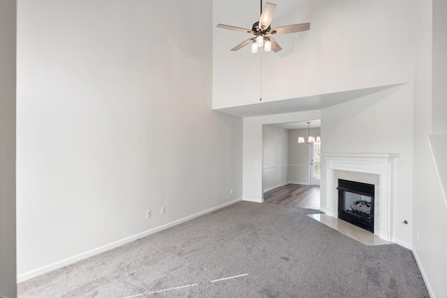 unfurnished living room with a high ceiling, ceiling fan with notable chandelier, and light colored carpet