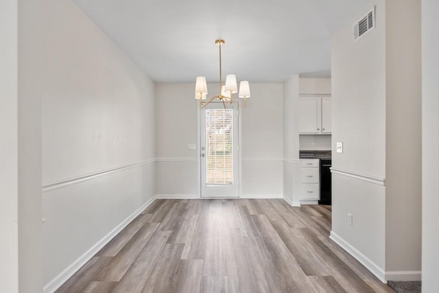 unfurnished dining area featuring light wood-type flooring and a notable chandelier