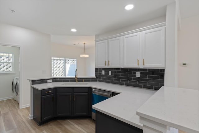 kitchen with washer and clothes dryer, pendant lighting, sink, light hardwood / wood-style flooring, and white cabinetry