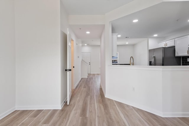 kitchen featuring white cabinets, stainless steel fridge with ice dispenser, sink, and light hardwood / wood-style flooring