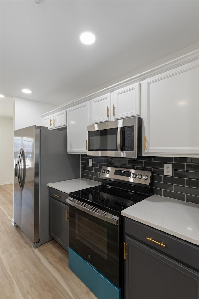 kitchen featuring white cabinets, appliances with stainless steel finishes, backsplash, and light hardwood / wood-style floors