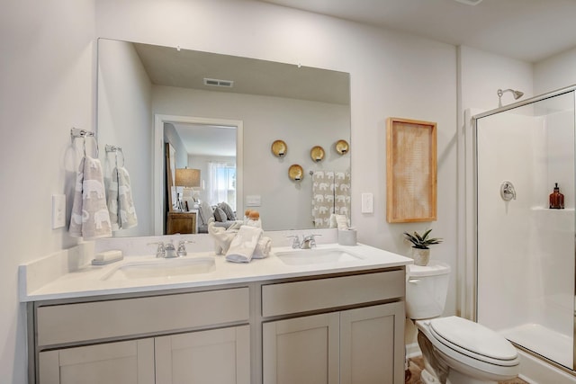 bathroom featuring a shower with door, vanity, and toilet