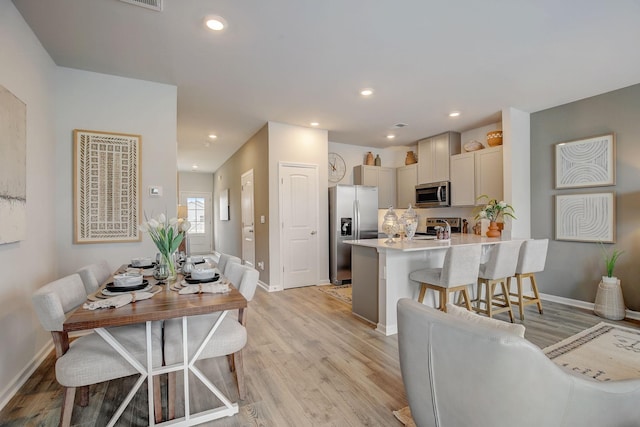 kitchen featuring a kitchen breakfast bar, light wood-type flooring, kitchen peninsula, and appliances with stainless steel finishes