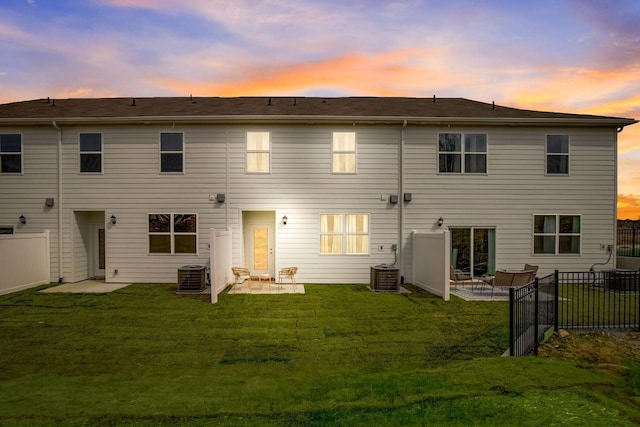 back house at dusk featuring a yard, central AC, and a patio area