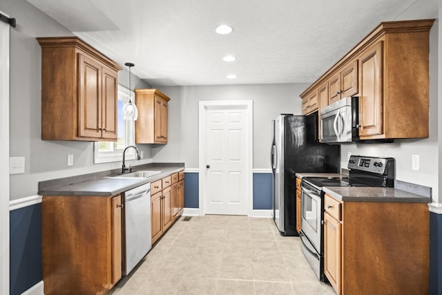 kitchen featuring sink, stainless steel appliances, a barn door, pendant lighting, and light tile patterned floors