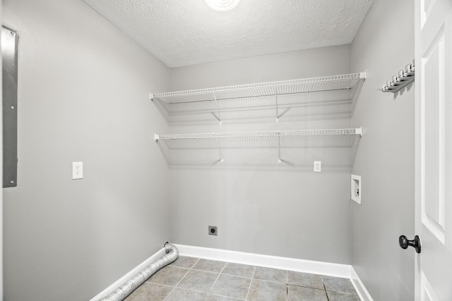 washroom featuring electric dryer hookup, light tile patterned floors, washer hookup, and a textured ceiling