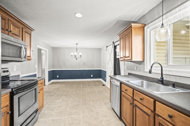 kitchen featuring sink, hanging light fixtures, a barn door, stainless steel appliances, and a chandelier