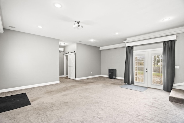 unfurnished living room with carpet, a barn door, an AC wall unit, and french doors