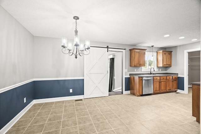 kitchen featuring dishwasher, pendant lighting, a barn door, and a textured ceiling