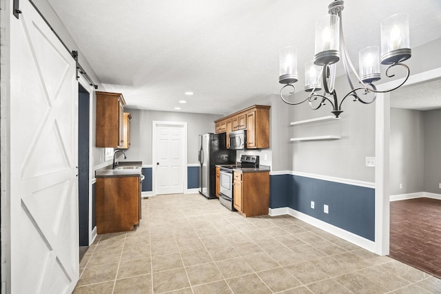 kitchen with an inviting chandelier, sink, a barn door, light tile patterned floors, and stainless steel appliances