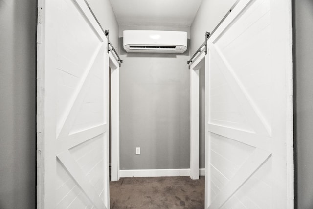 spacious closet featuring dark colored carpet, a barn door, and an AC wall unit