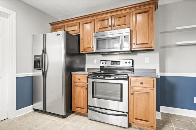 kitchen with light tile patterned floors, a textured ceiling, and stainless steel appliances