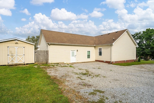 rear view of property featuring a storage unit and a lawn