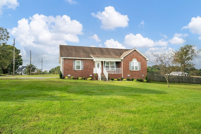 ranch-style house featuring covered porch and a front yard