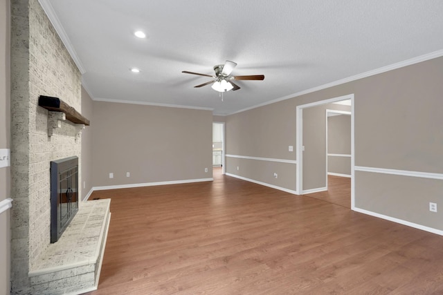 unfurnished living room with ceiling fan, crown molding, wood-type flooring, and a fireplace