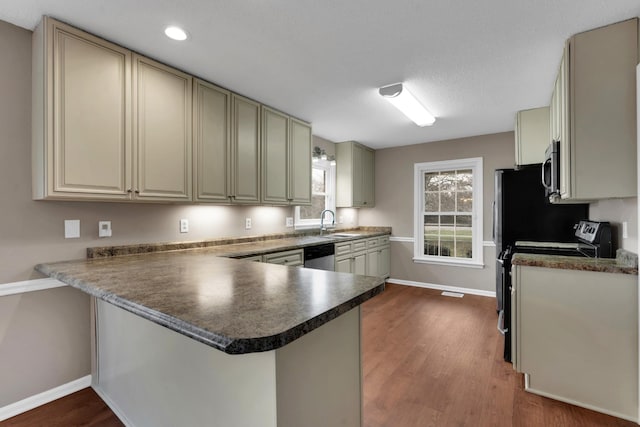 kitchen with dark hardwood / wood-style flooring, kitchen peninsula, sink, and appliances with stainless steel finishes