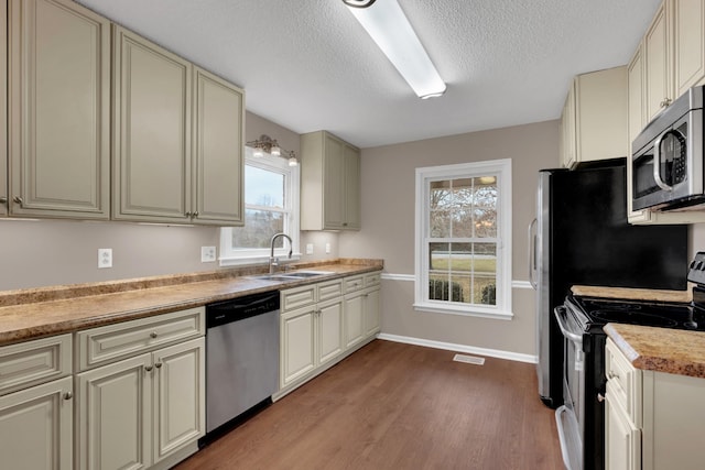 kitchen featuring a wealth of natural light, cream cabinets, stainless steel appliances, and sink