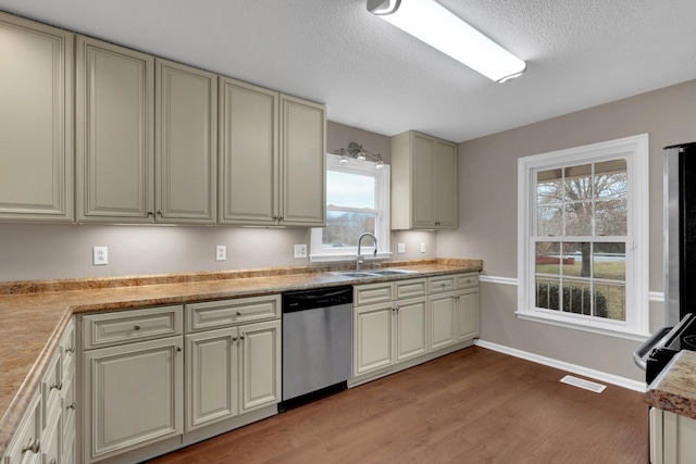 kitchen featuring dishwasher, sink, cream cabinets, a textured ceiling, and hardwood / wood-style flooring