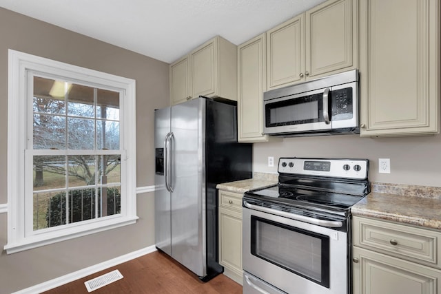 kitchen with cream cabinetry, appliances with stainless steel finishes, and dark wood-type flooring