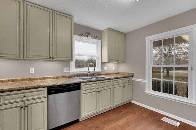 kitchen featuring sink, cream cabinetry, stainless steel dishwasher, and light hardwood / wood-style floors