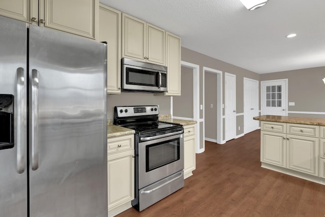 kitchen with cream cabinetry, light stone countertops, and appliances with stainless steel finishes