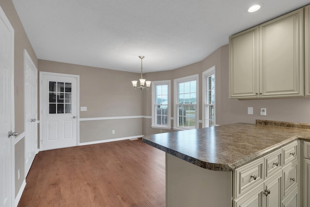 kitchen featuring dark hardwood / wood-style floors, kitchen peninsula, a chandelier, pendant lighting, and cream cabinetry