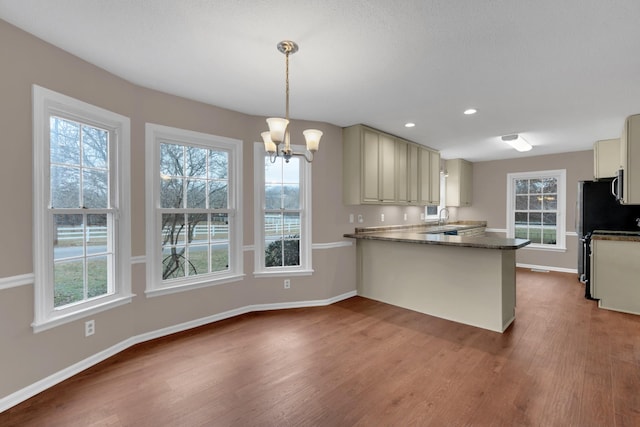 kitchen featuring cream cabinets, kitchen peninsula, hanging light fixtures, and a chandelier