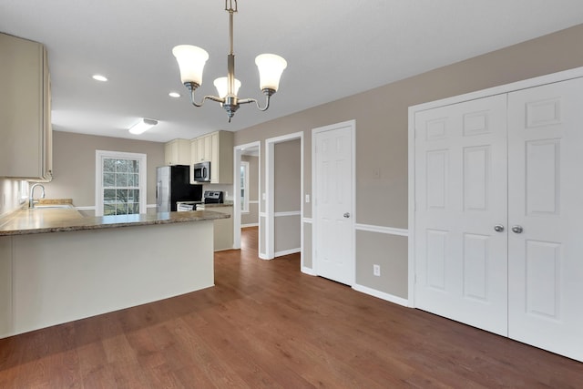 kitchen featuring light stone counters, stainless steel appliances, sink, an inviting chandelier, and hanging light fixtures