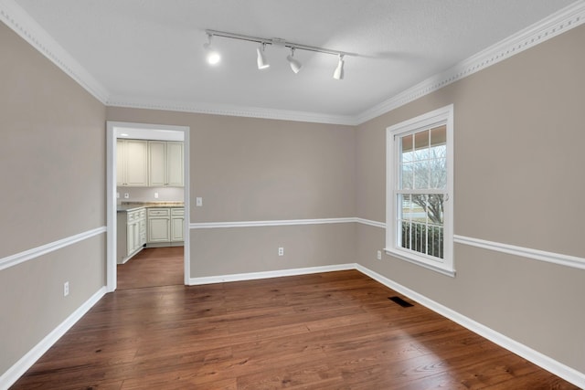 spare room with a textured ceiling, hardwood / wood-style flooring, track lighting, and crown molding