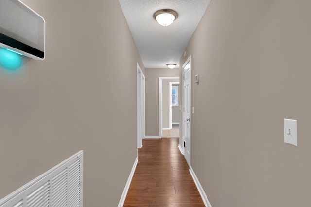 hall with dark hardwood / wood-style flooring and a textured ceiling