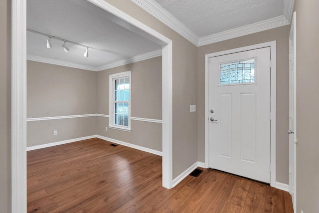 entrance foyer featuring wood-type flooring, rail lighting, a textured ceiling, and crown molding