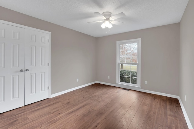 unfurnished bedroom featuring a closet, ceiling fan, hardwood / wood-style floors, and a textured ceiling