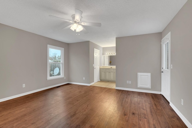 unfurnished living room featuring ceiling fan, a textured ceiling, and light wood-type flooring