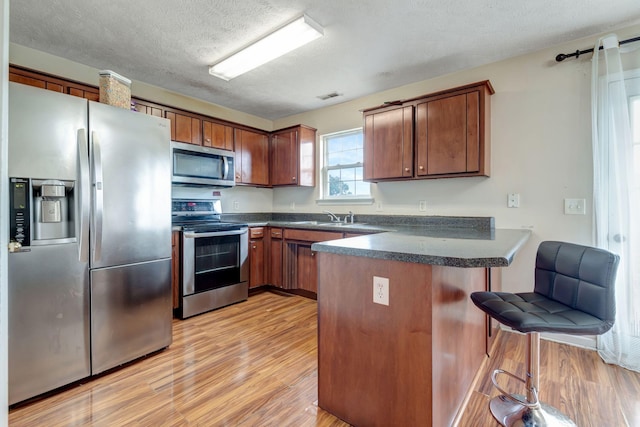 kitchen featuring a textured ceiling, sink, kitchen peninsula, and stainless steel appliances