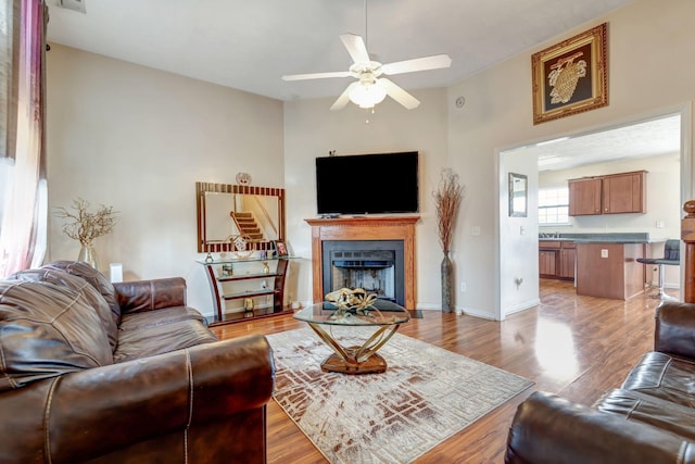 living room with ceiling fan, sink, and light hardwood / wood-style floors