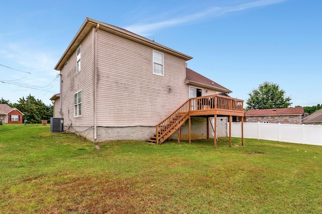 rear view of property with a lawn, central air condition unit, and a wooden deck