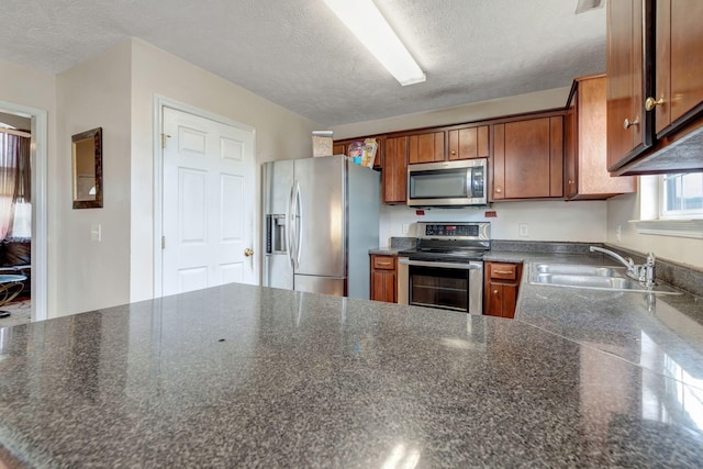 kitchen with a textured ceiling, sink, and appliances with stainless steel finishes